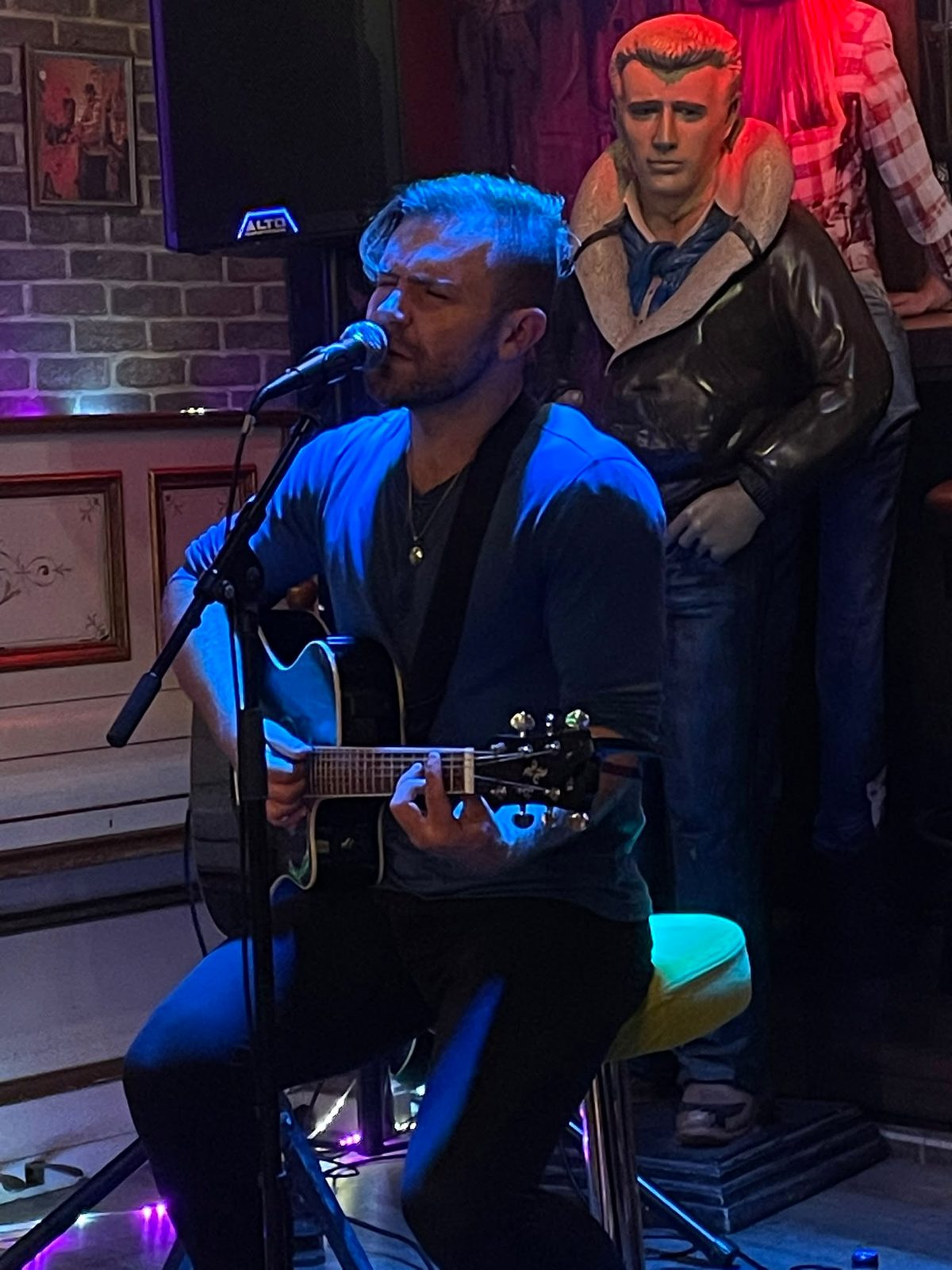 Zack seated with guitar and microphone at Tennessee, Condeixa